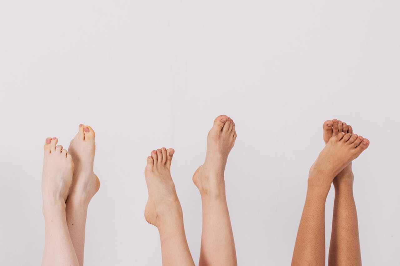 Multiple pairs of raised feet with varying skin tones, illustrating diverse foot conditions and the importance of foot monitoring for diabetes management