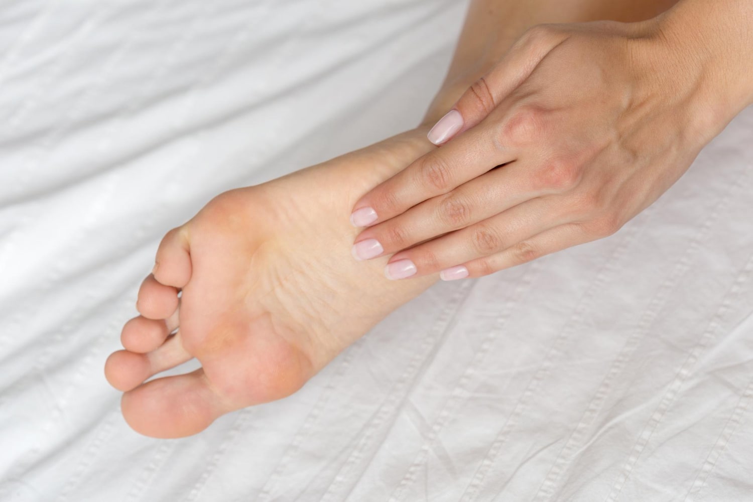 Woman examining the bottom of her foot for signs of a foot ulcer or skin irritation