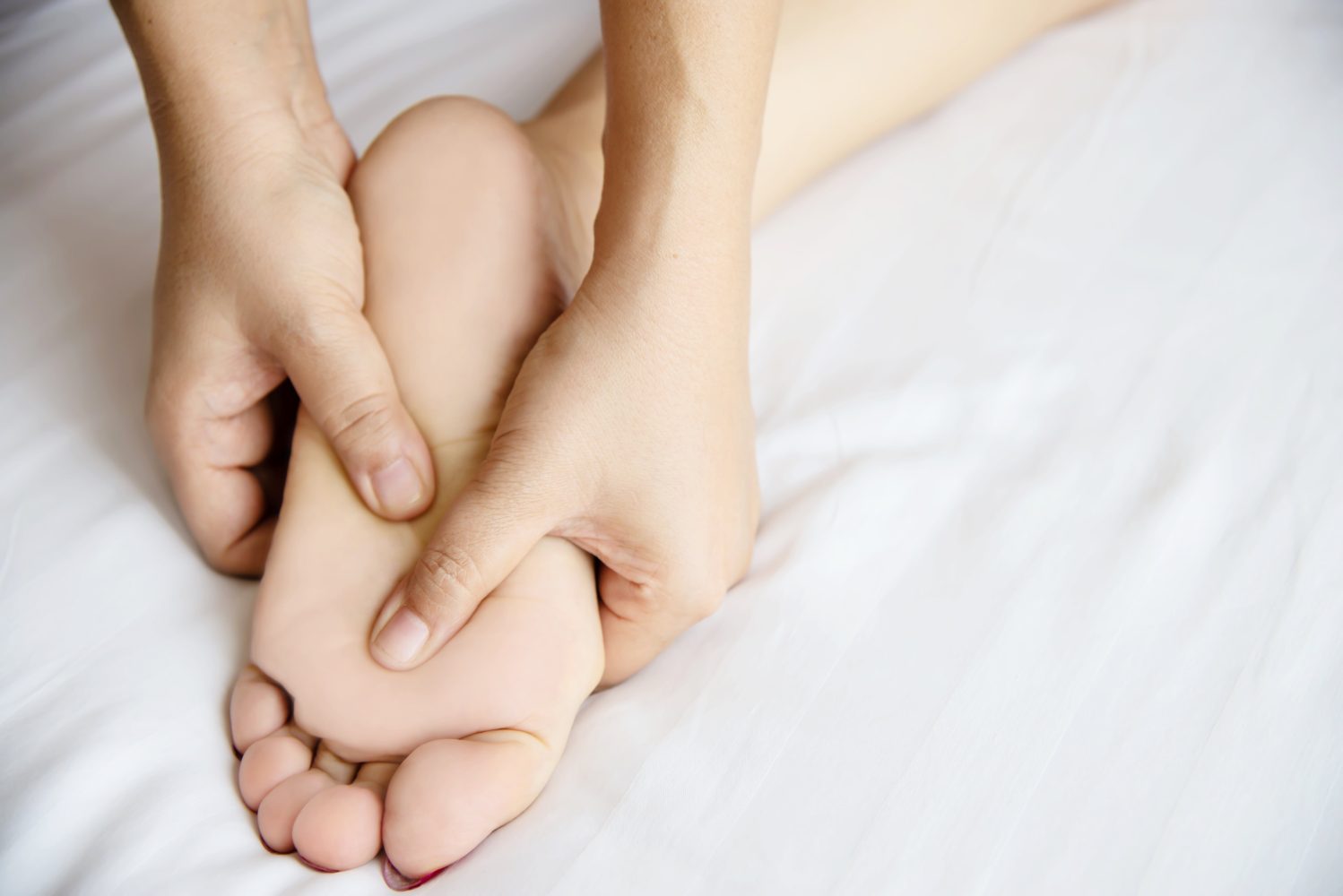 Close-up of a person massaging the sole of a foot, symbolizing the importance of foot care and circulation monitoring in managing diabetes-related skin conditions.