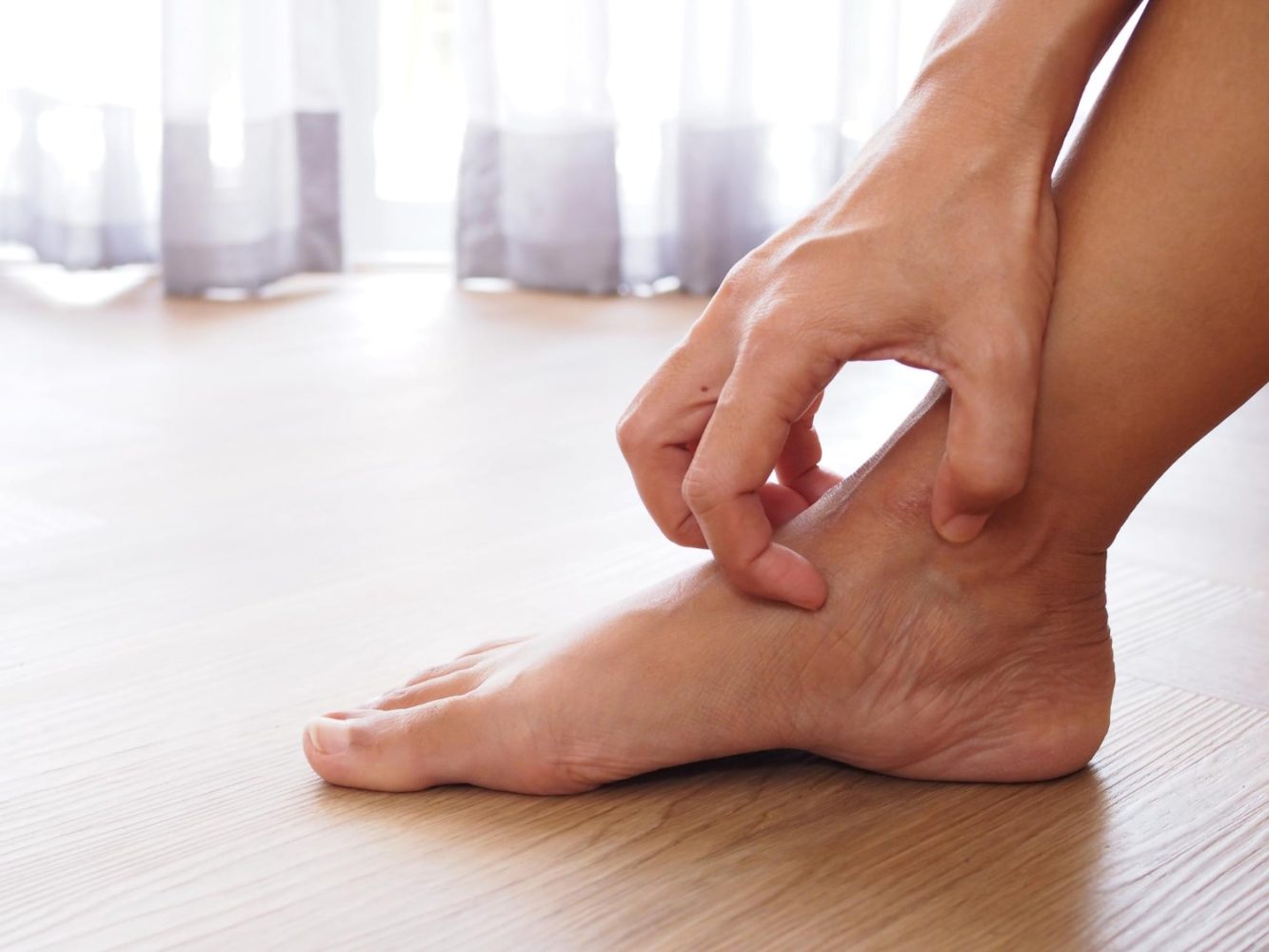 Close-up of a person scratching the ankle, depicting symptoms of diabetic skin irritation or neuropathic itching in the lower extremities.
